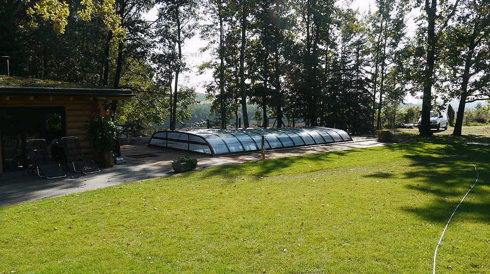 Dezent flache Schwimmbadüberdachung in Tannengrün